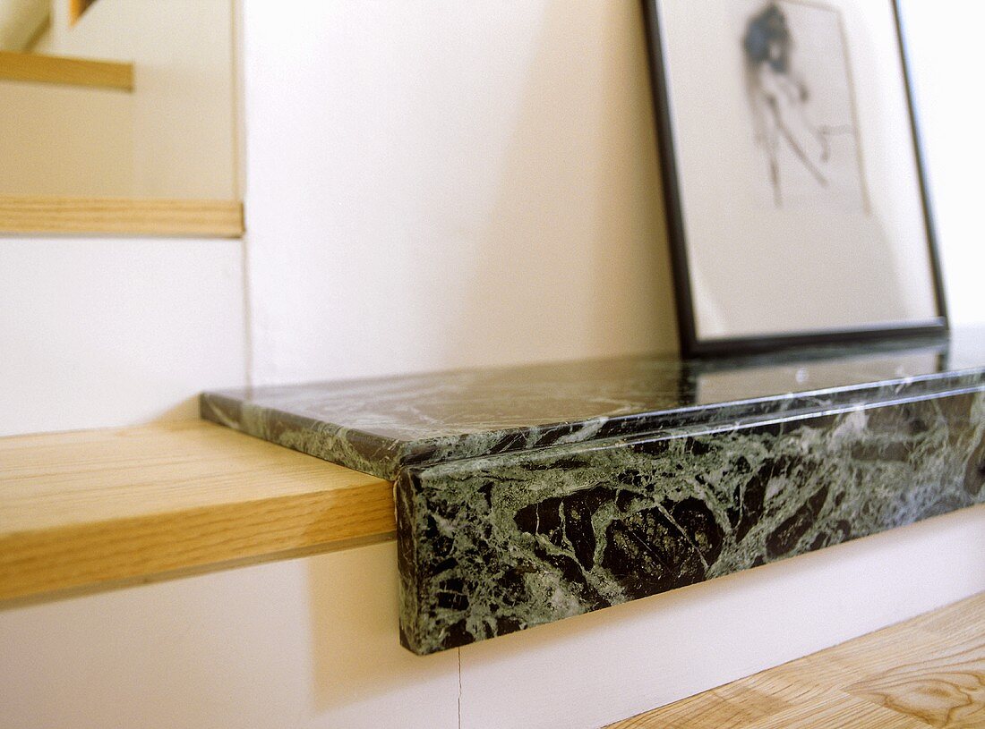 A detail of a modern, sitting room, wooden and marble step, drawing in frame,
