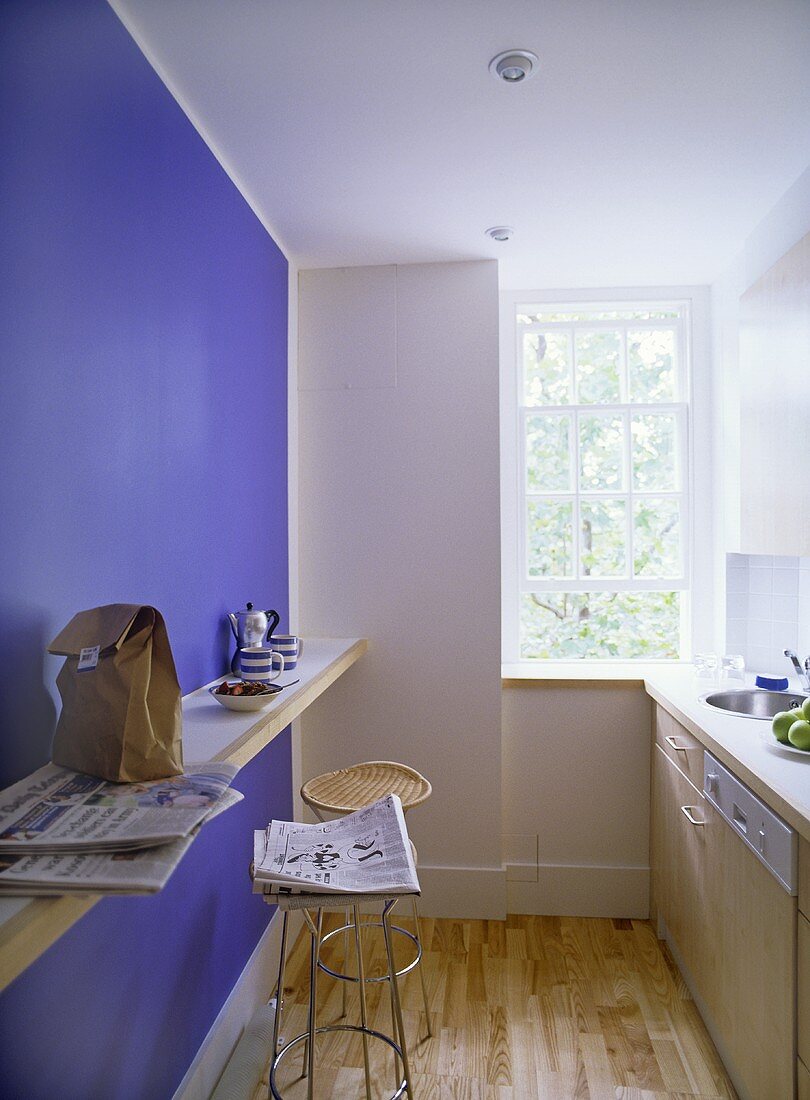 Moderne Küche mit Thekenablage und Barhocker vor blauer Wand