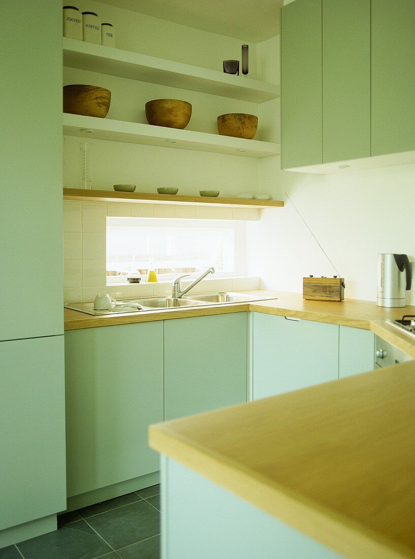 Shelving above sink in kitchen with green fitted units