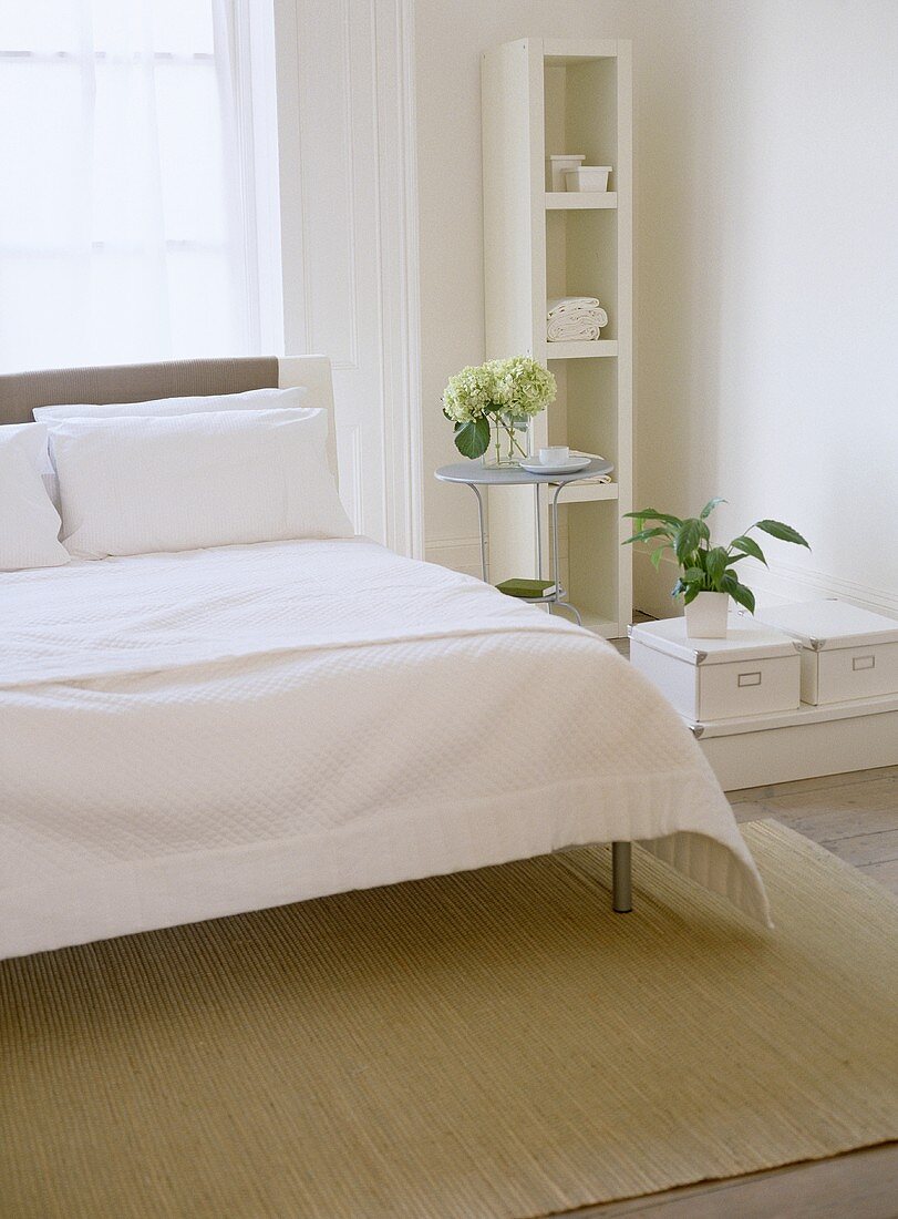 Schlafzimmer mit weisser Bettwäsche und Regal