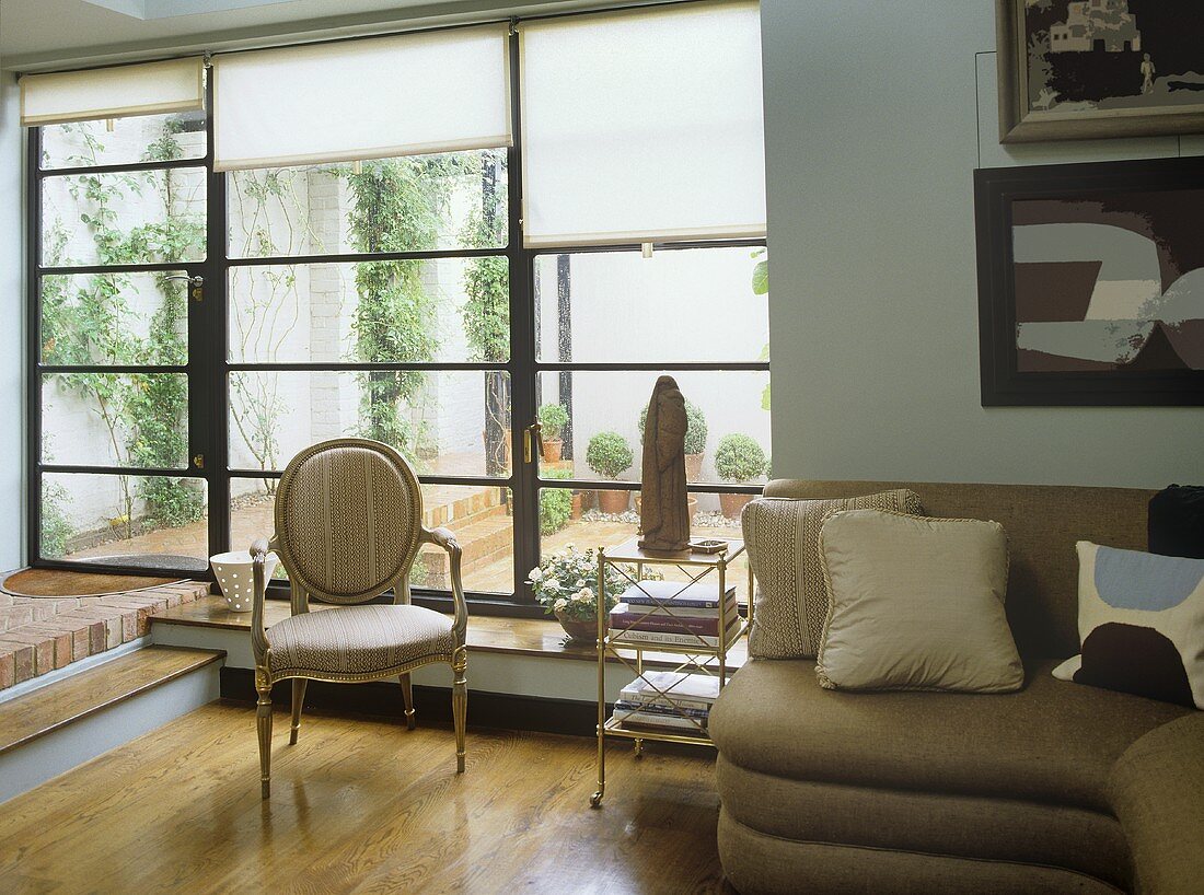 Wohnzimmer im Landhausstil mit Sofa übereck und Rokokosessel vor Terrassenfenster