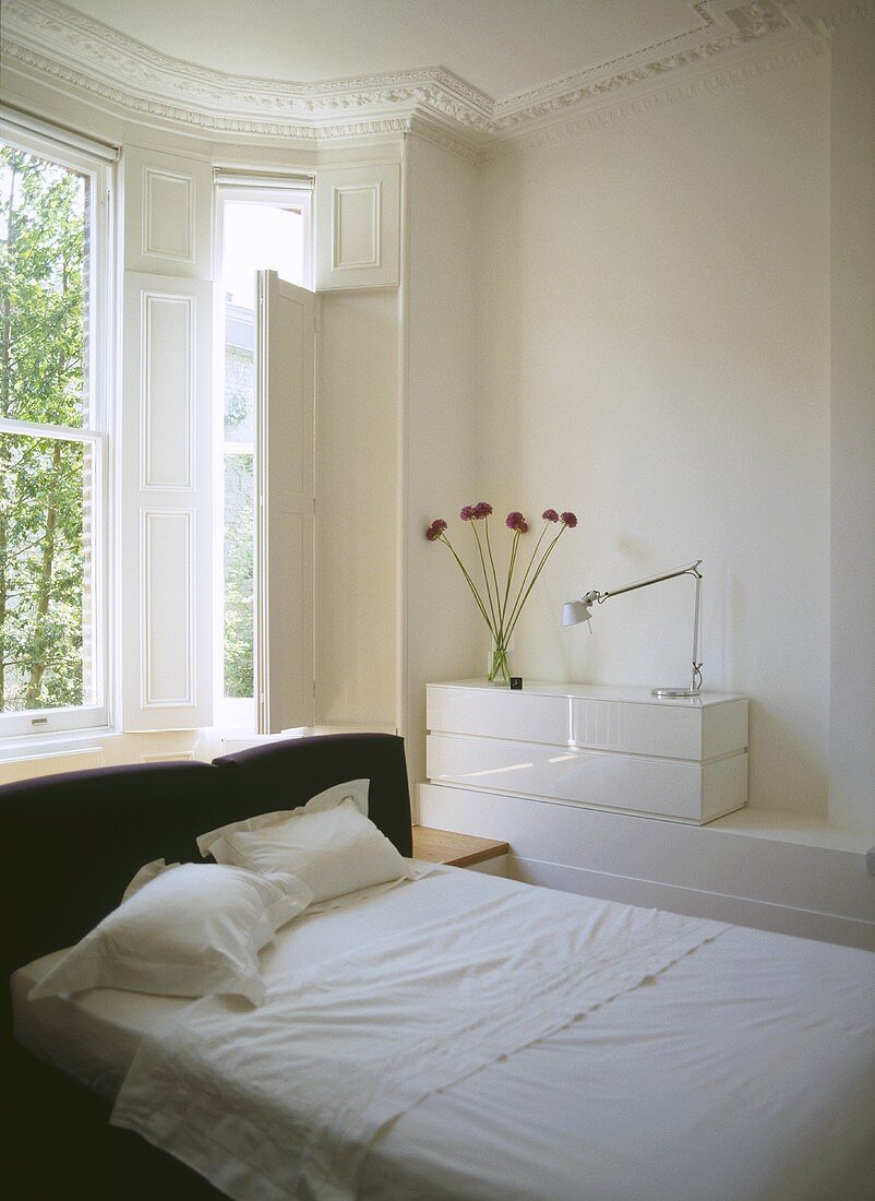 Modernes Schlafzimmer mit Doppelbett und gepolstertem Kopfteil im Erker eines Altbaus