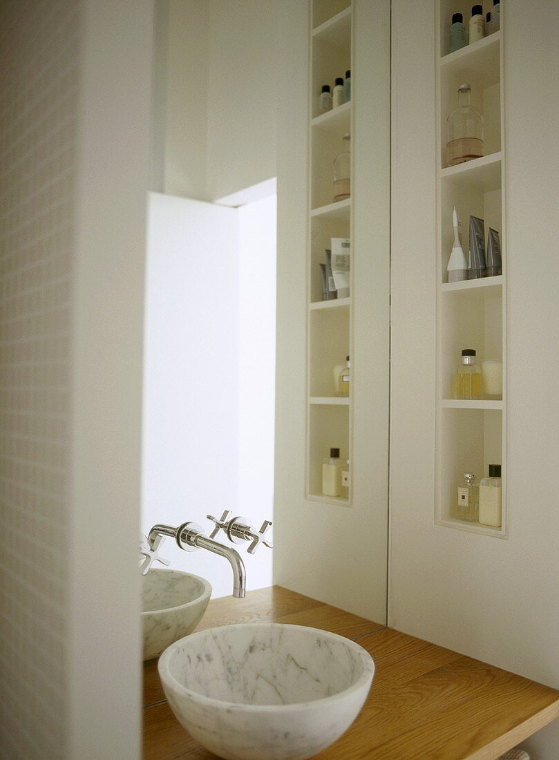 Modernes Bad mit Waschschüssel vor Spiegel und Einbauregal mit Badutensilien