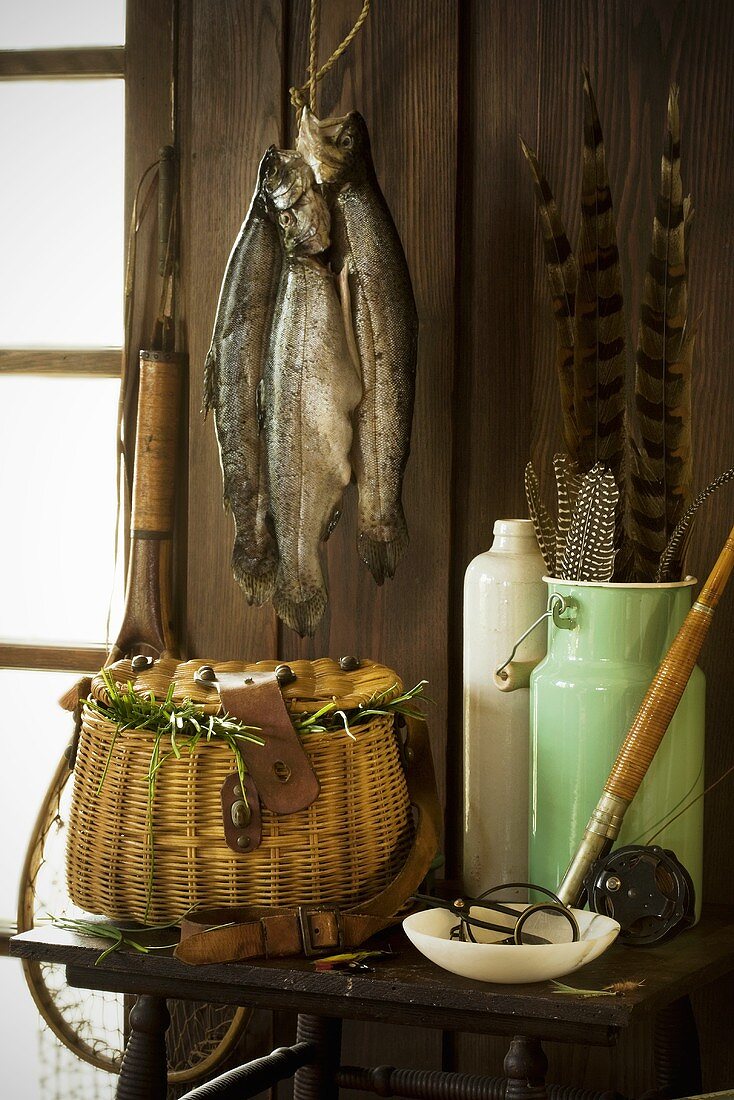 Aufgehängte, frisch gefangene Forellen & Fischerei-Utensilien auf Tisch in einer Fischerhütte
