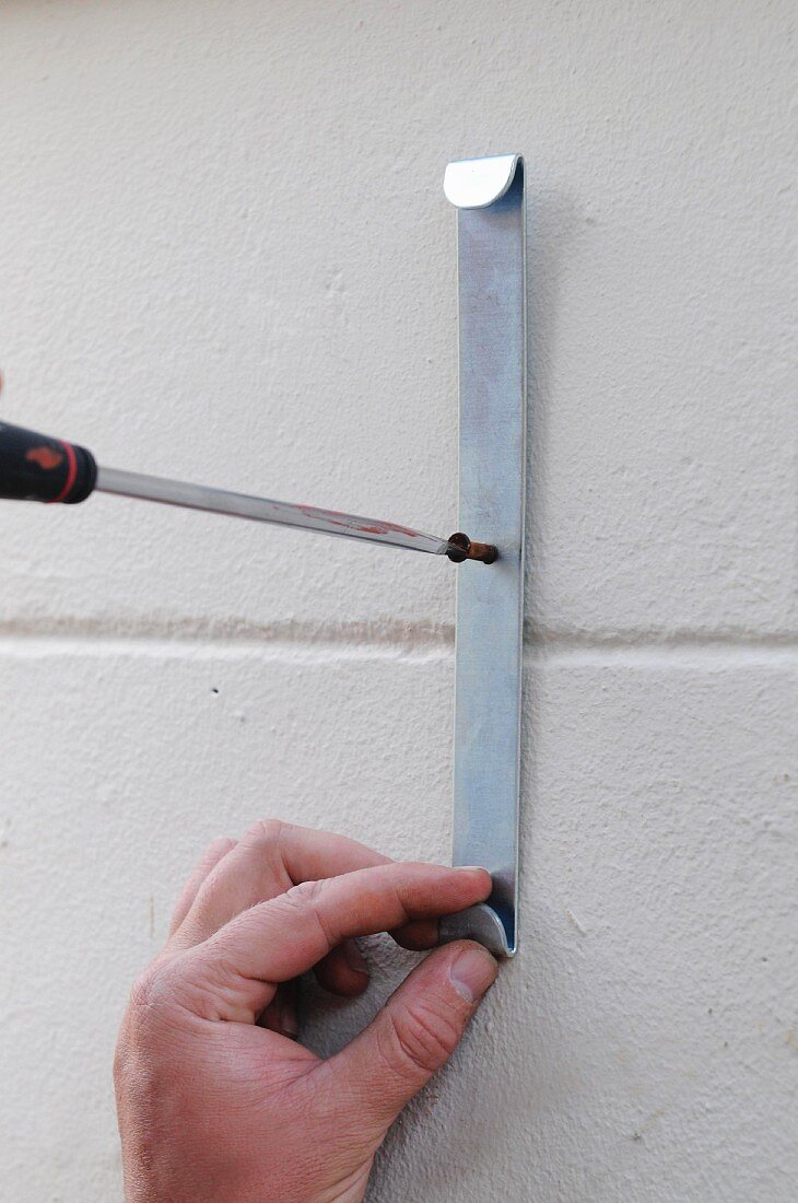 A hook being screwed on the wall