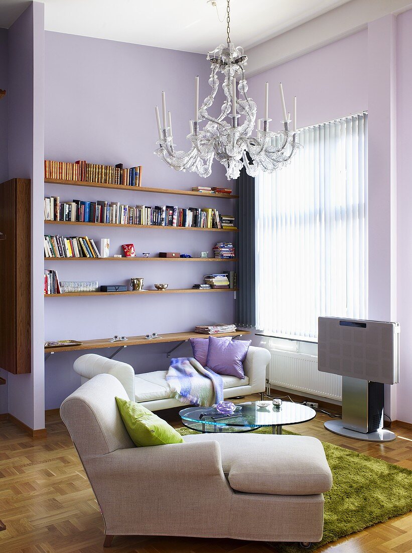 Eine Chaiselounge, ein Tagesbett und Regale in einem Wohnzimmer mit rosa Wänden