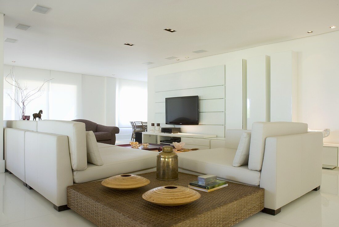 Ein elegantes Wohnzimmer mit Sitzmöbeln, einem Couchtisch und einem Flachfernesehr