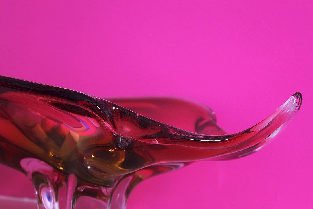 Dekorative rote Glasschale vor pinkfarbenem Hintergrund