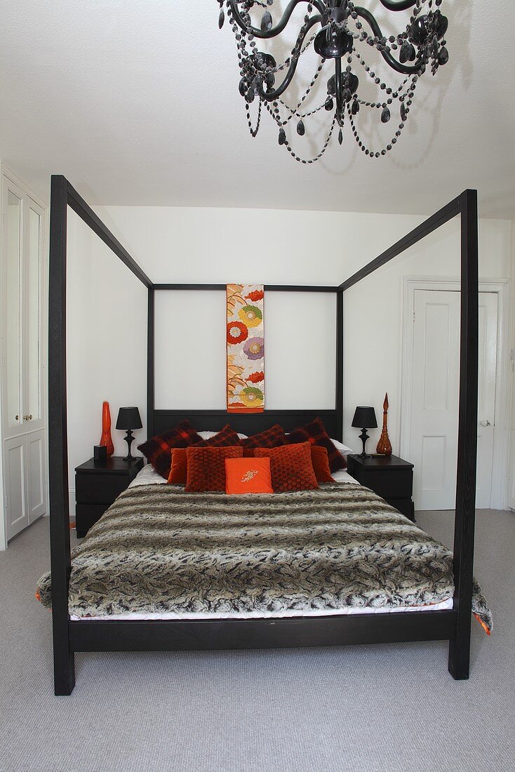 Ein Himmelbett mit Dekokissen und Tagesdecke in einem Schlafzimmer