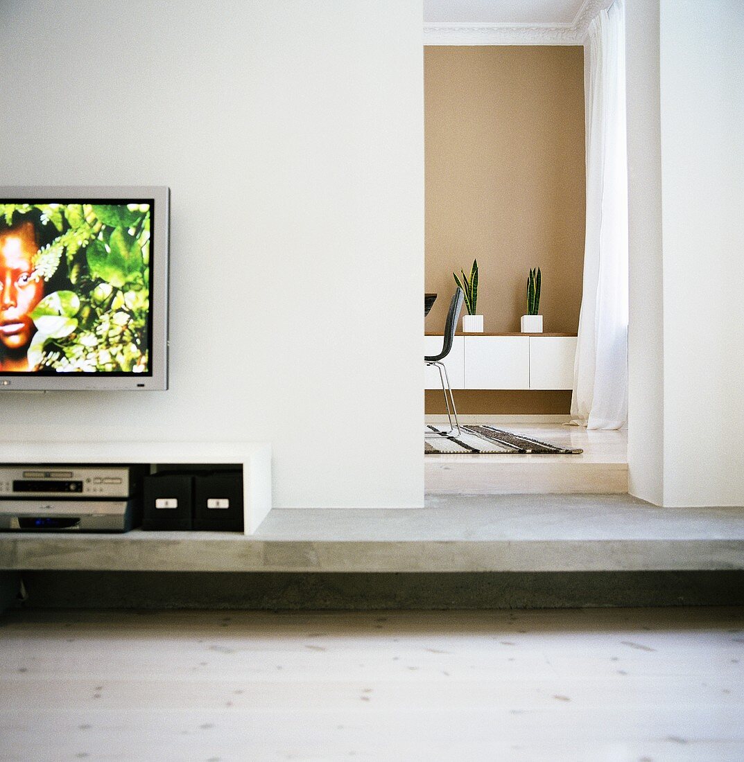 Ein Flachfernseher an der Wand über einem Sideboard mit Multimediageräten