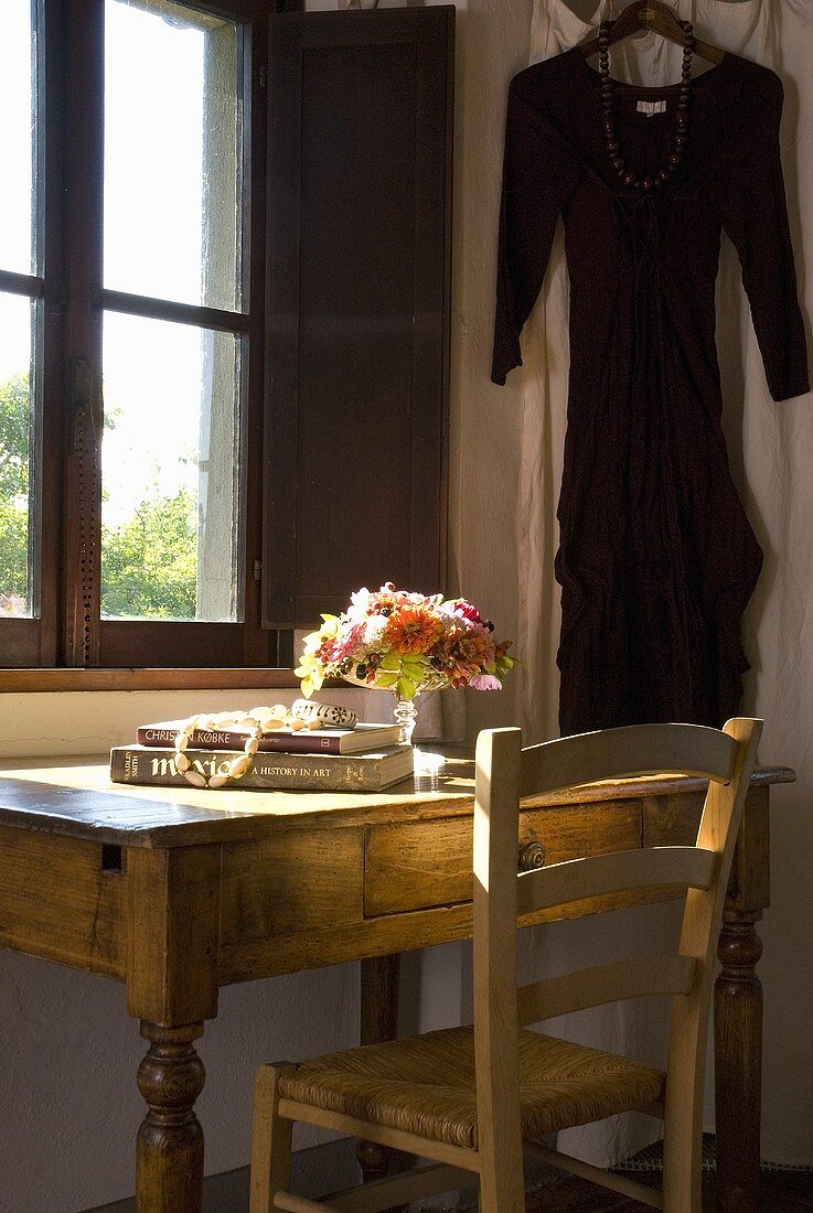 A rustic wooden desk and a chair in front of a window