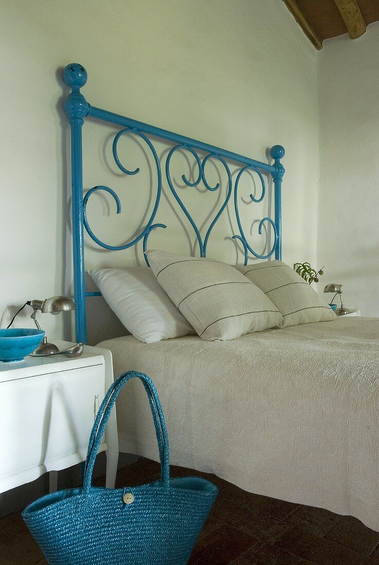 Ein blaues schmiedeeisernes Bett mit weisser Bettwäsche