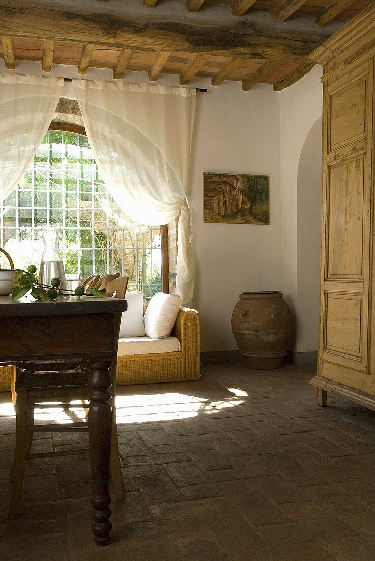 Ein Esstisch mit Stühlen und ein Rattansofa vor dem Bogenfenster in einem Esszimmer