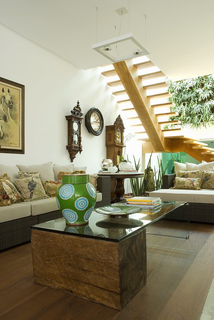 A glass topped table and Dedon furniture in a sitting area with a flight of stairs in the background