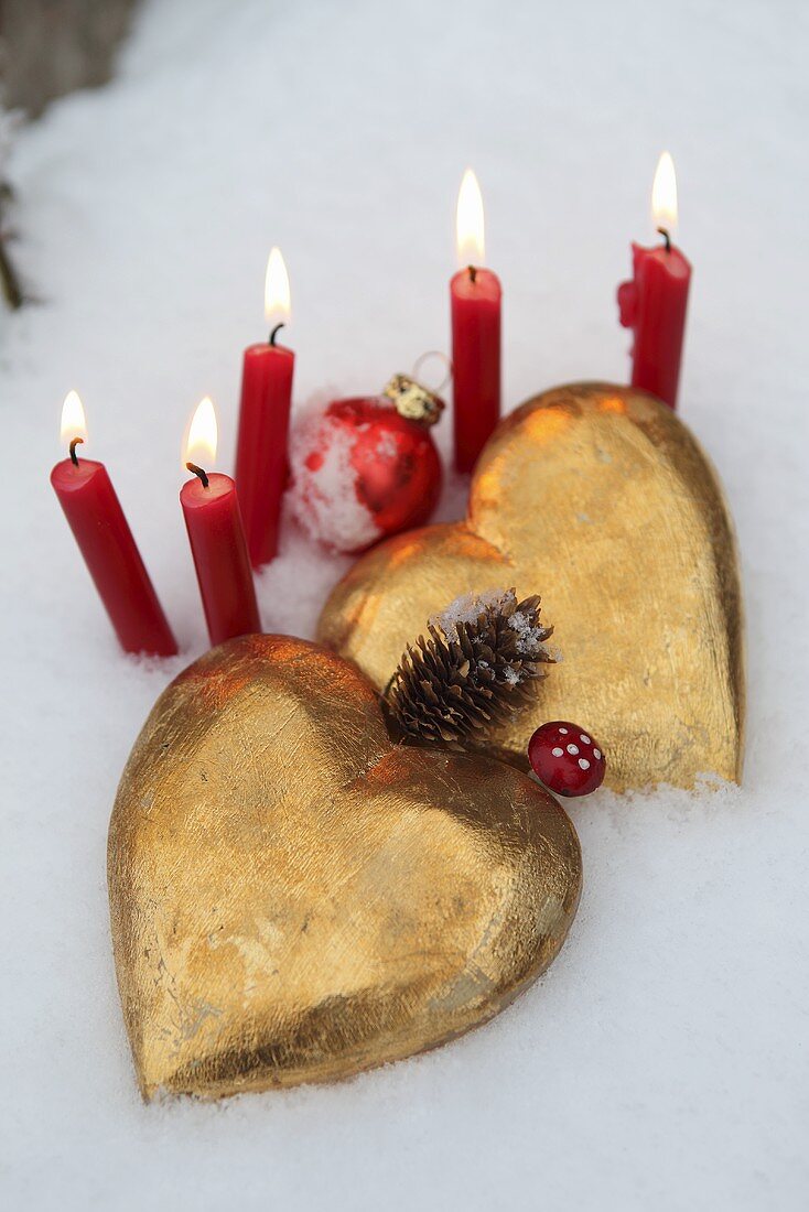 Golden hearts and red candles in the snow