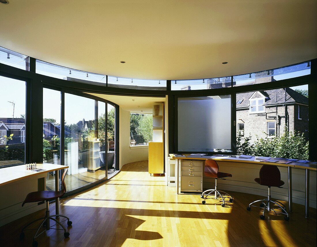 Open-plan room in contemporary penthouse with curved desk below window