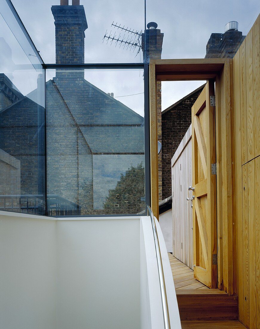 Verglaster Treppenaufgang und offenstehende Tür mit Blick auf Dachterrasse
