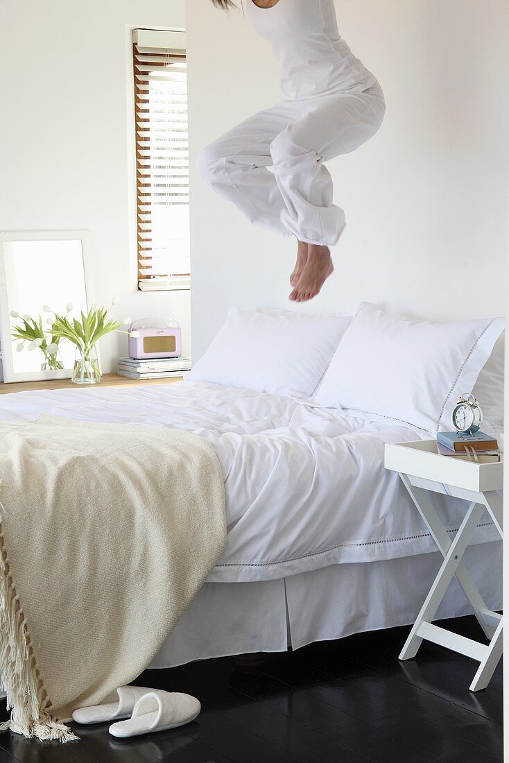 Young woman jumping on a bed