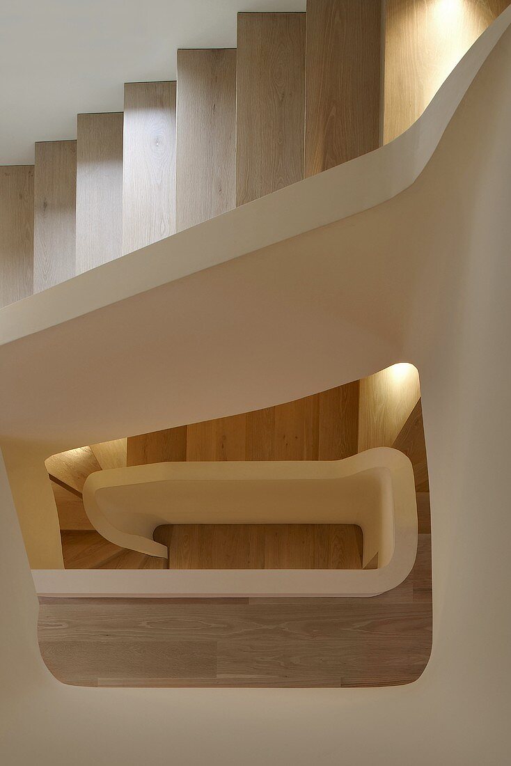 Blick durch Treppenauge eines modernen mehrstöckigen Wohnhauses auf Holzstufen