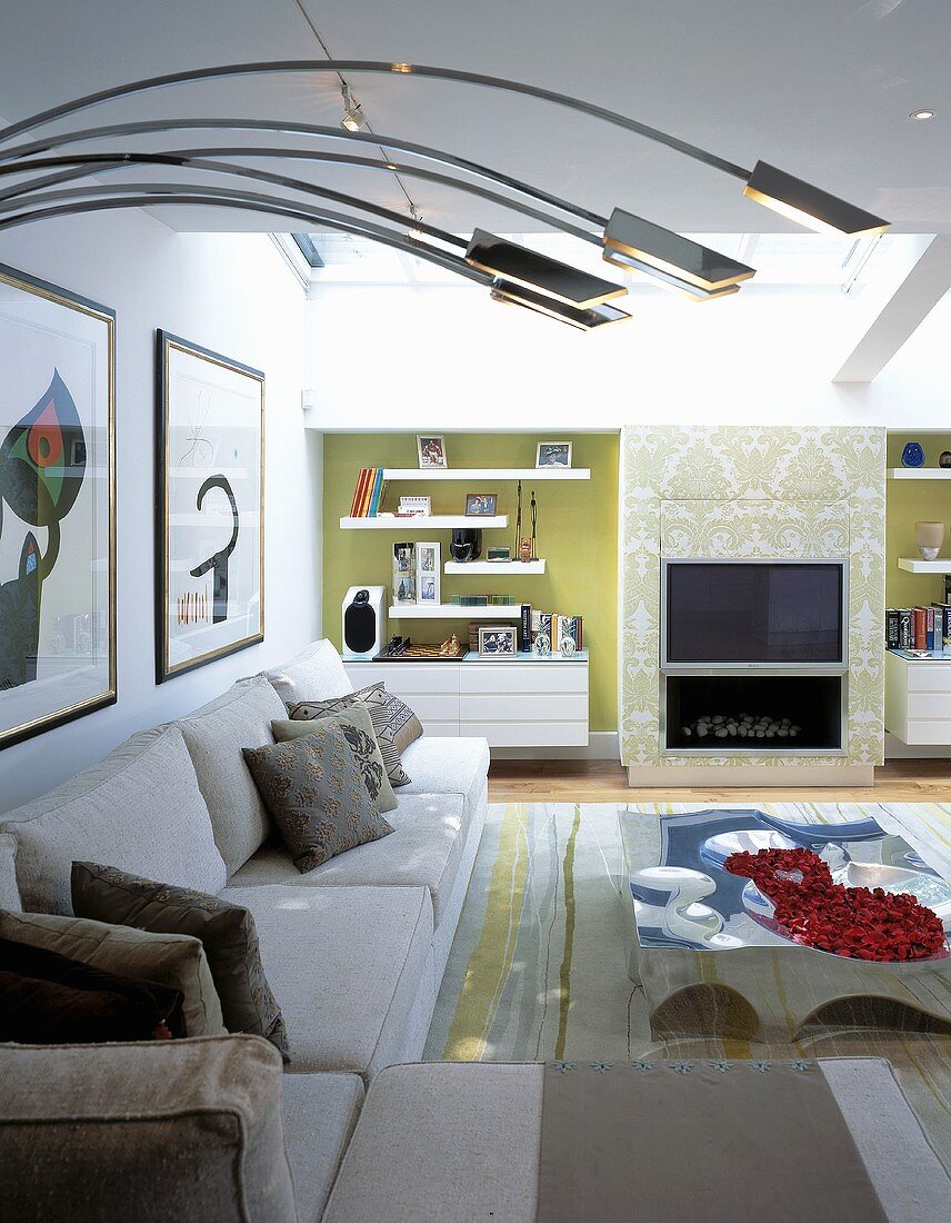 Modern sectional sofa and curved stainless steel lamp bodies in front of a fireplace and built-ins in niches