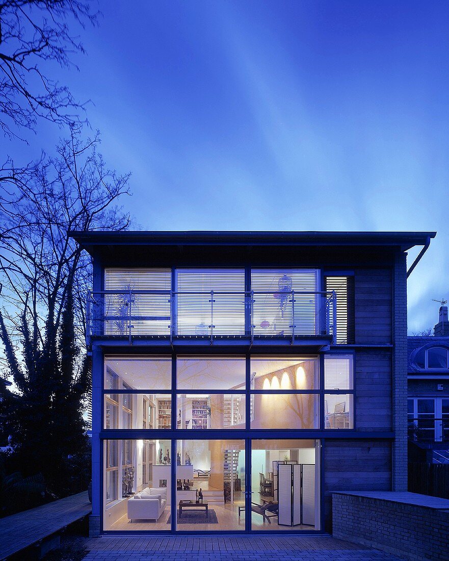 Zeitgenössisches Wohnhaus in Dämmerlichtstimmung mit Glasfassade und Blick in beleuchtete Etagen