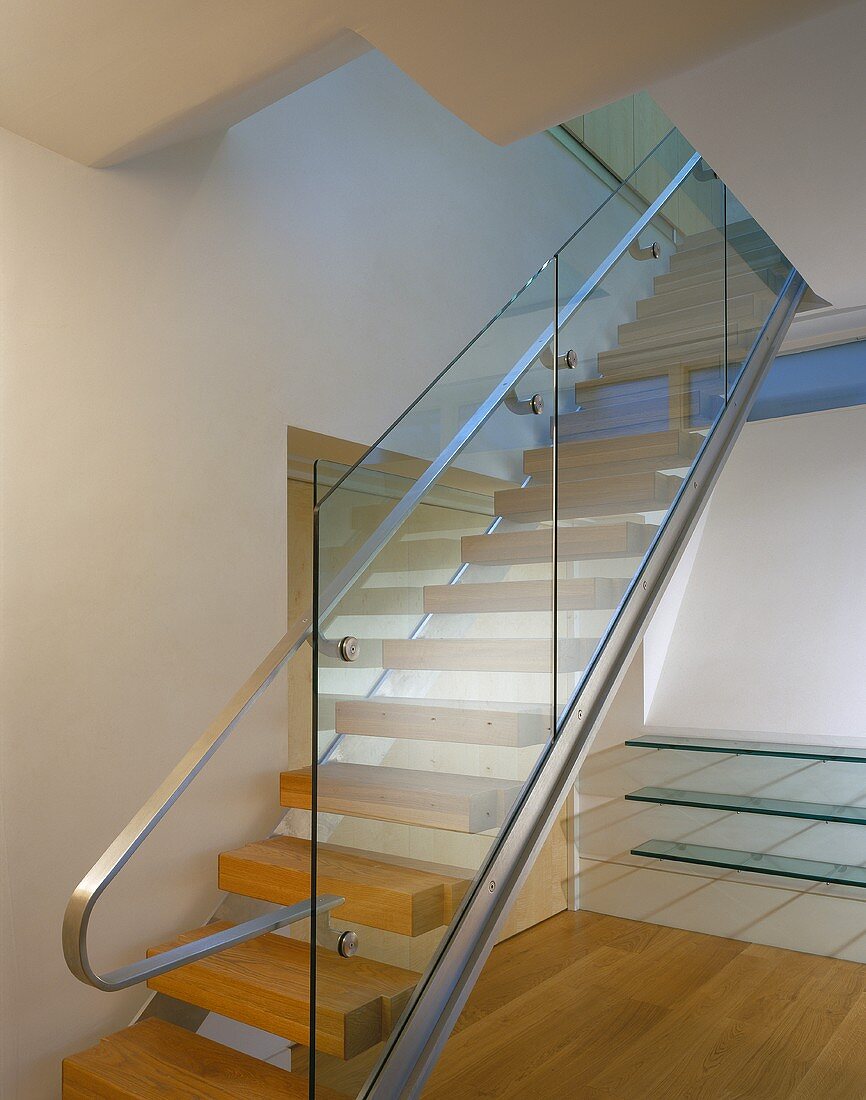 A modern stairway with a glass balustrade and a stainless steel handrail