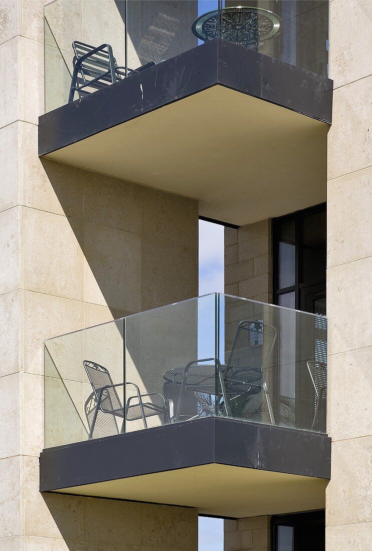 Section of a facade of a modern home, the balcony has a glass balustrade