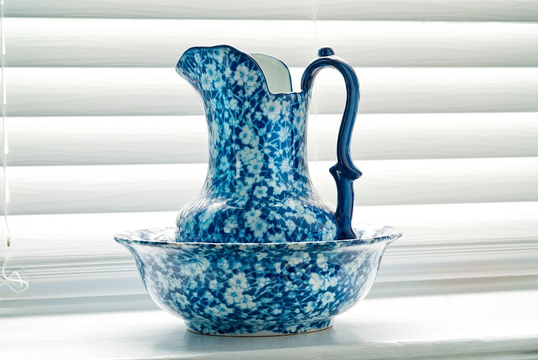 Antike Waschschüssel mit Wasserkrug auf Fensterbrett