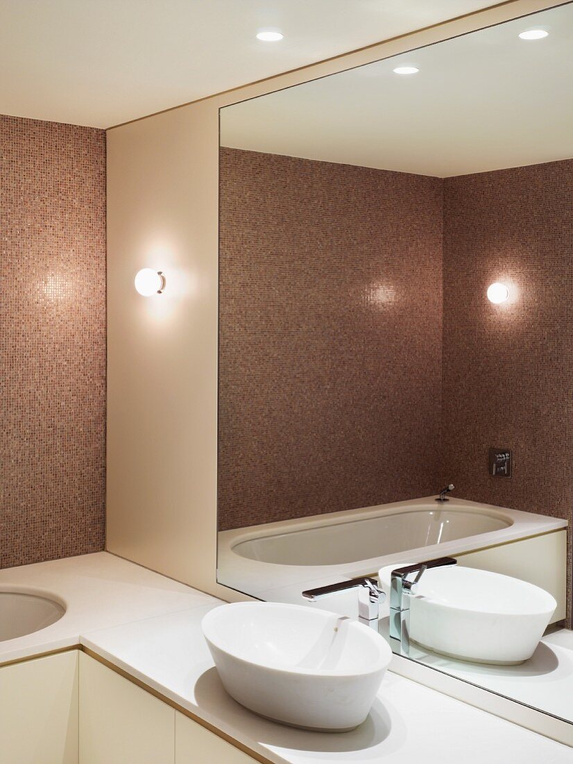 Rosafabenes modernes Bad mit weisser Waschschüssel vor grossem Wandspiegel