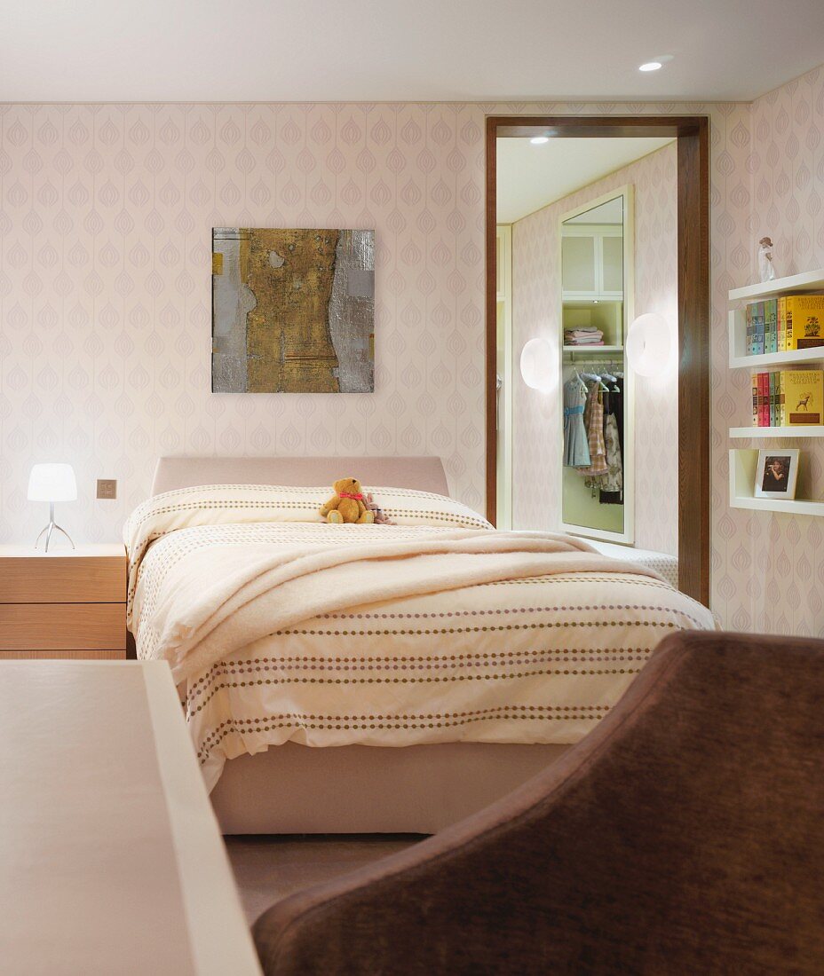 Doppelbett mit hellgelber Bettwäsche und heller gemusterter Tapete an Wand