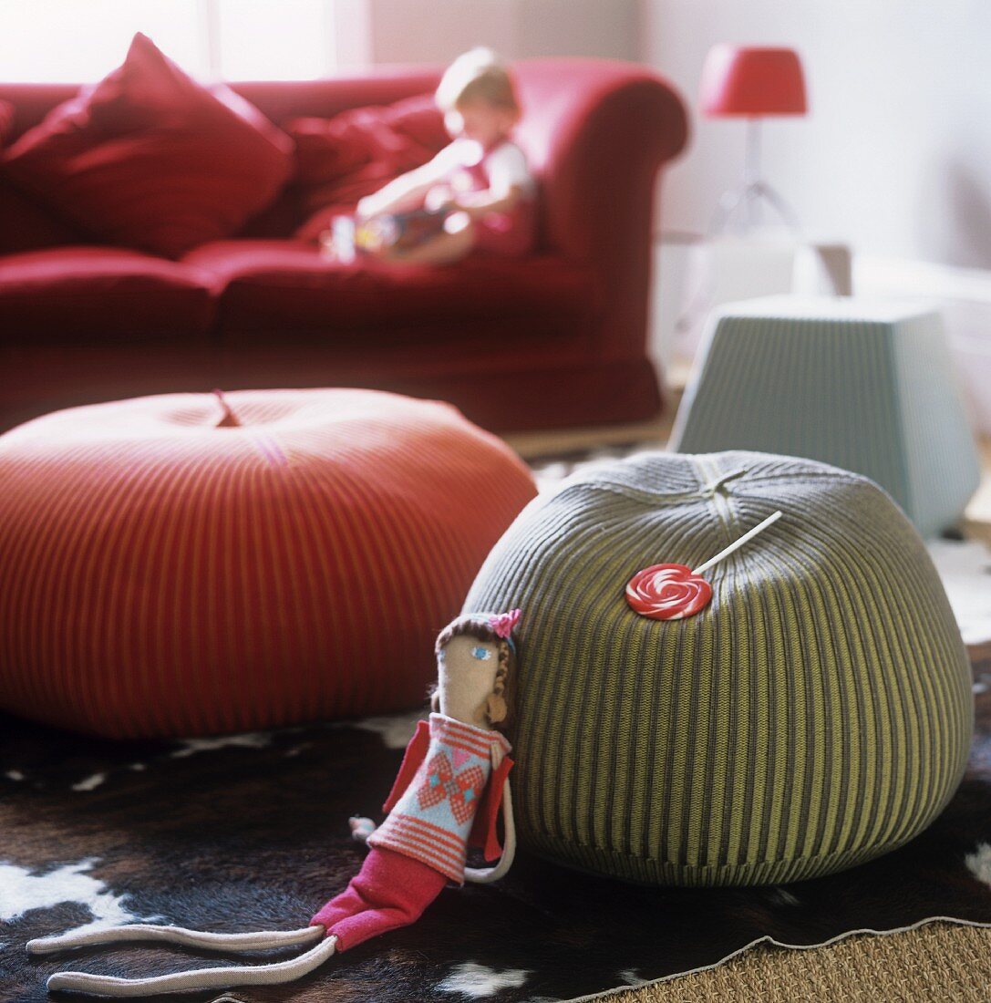 Floor cushions in front of a red sofa