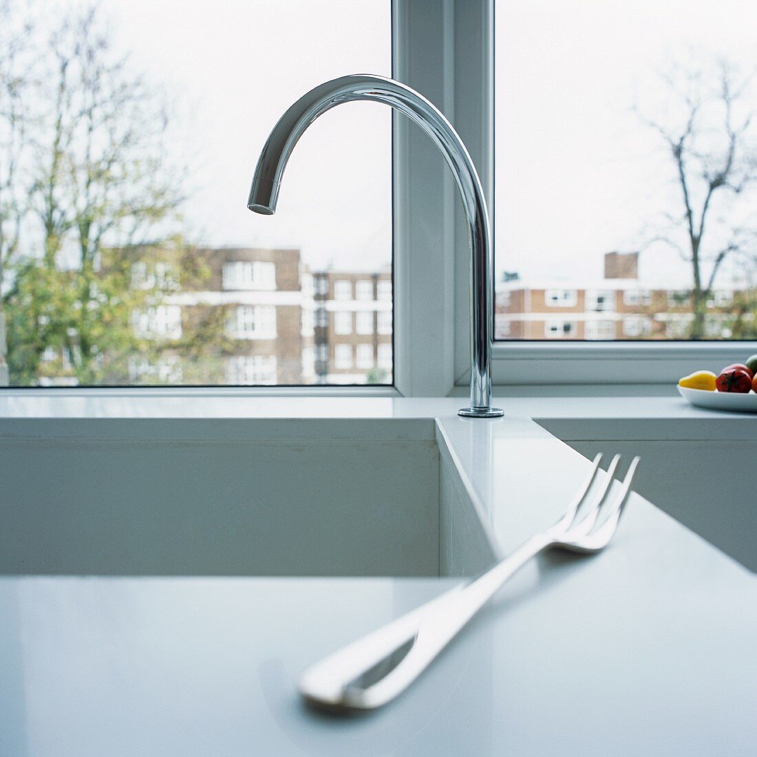 A fork on a sink in front of a window