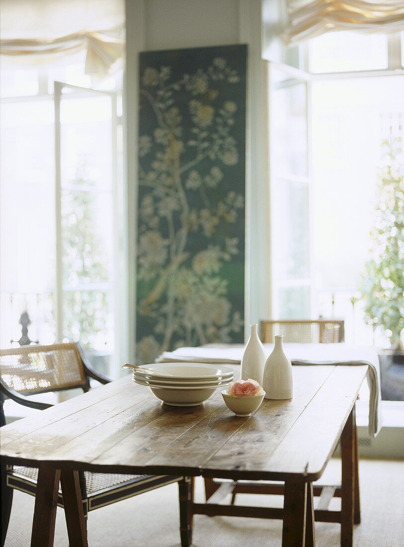 Traditionelles Esszimmer mit Geschirr auf rustikalem Holztisch und Stühlen