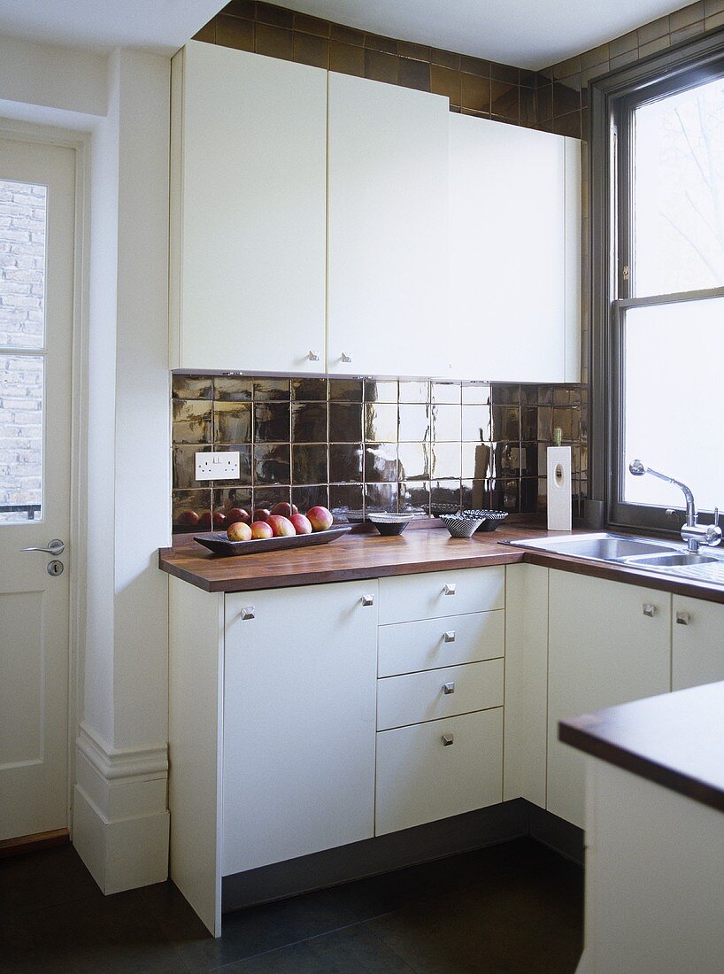 Moderne Küche mit weißen Schränken und dunklen Fliesen an Wand und Boden