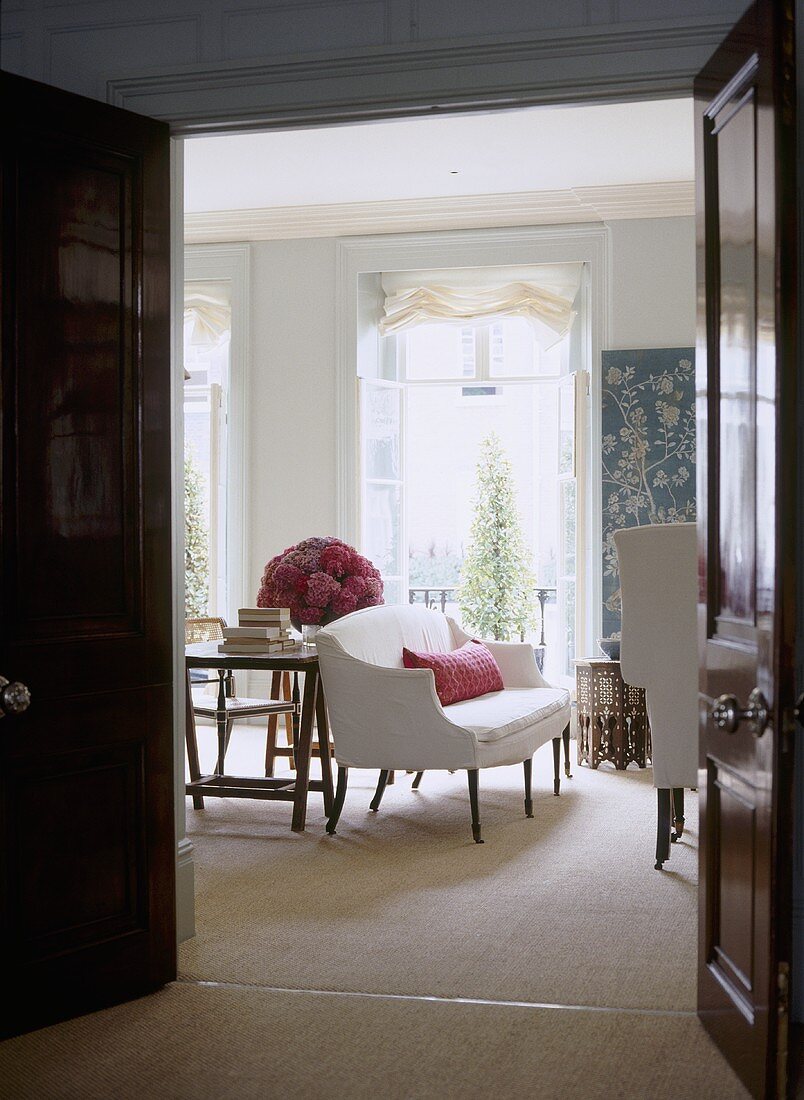 Blick durch offene Tür in traditionelles Wohnzimmer auf weisses Sofa und Fenster