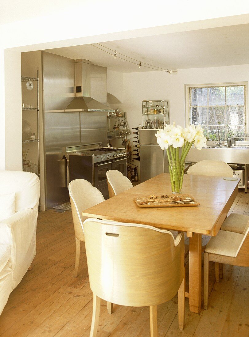 Open plan kitchen and dining area with stainless steel units and wooden table and chairs.