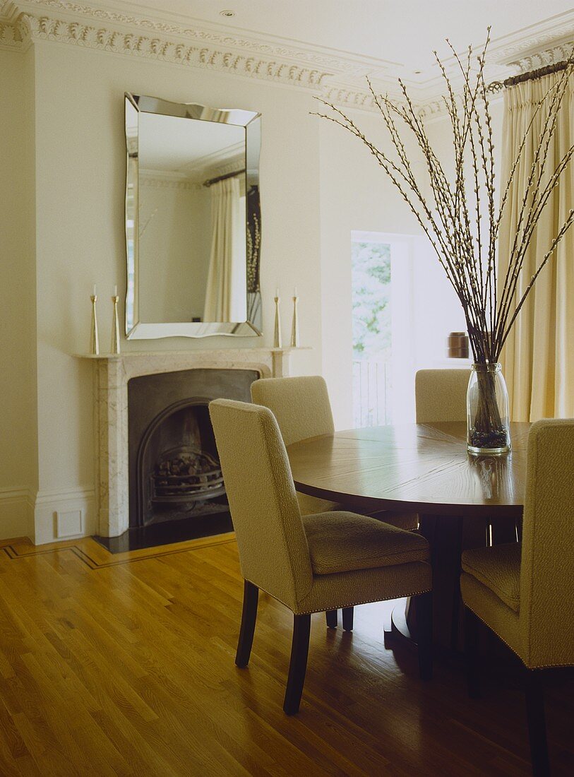 A modern, neutral dining room, round table with upholstered chairs, fireplace, wood floor,