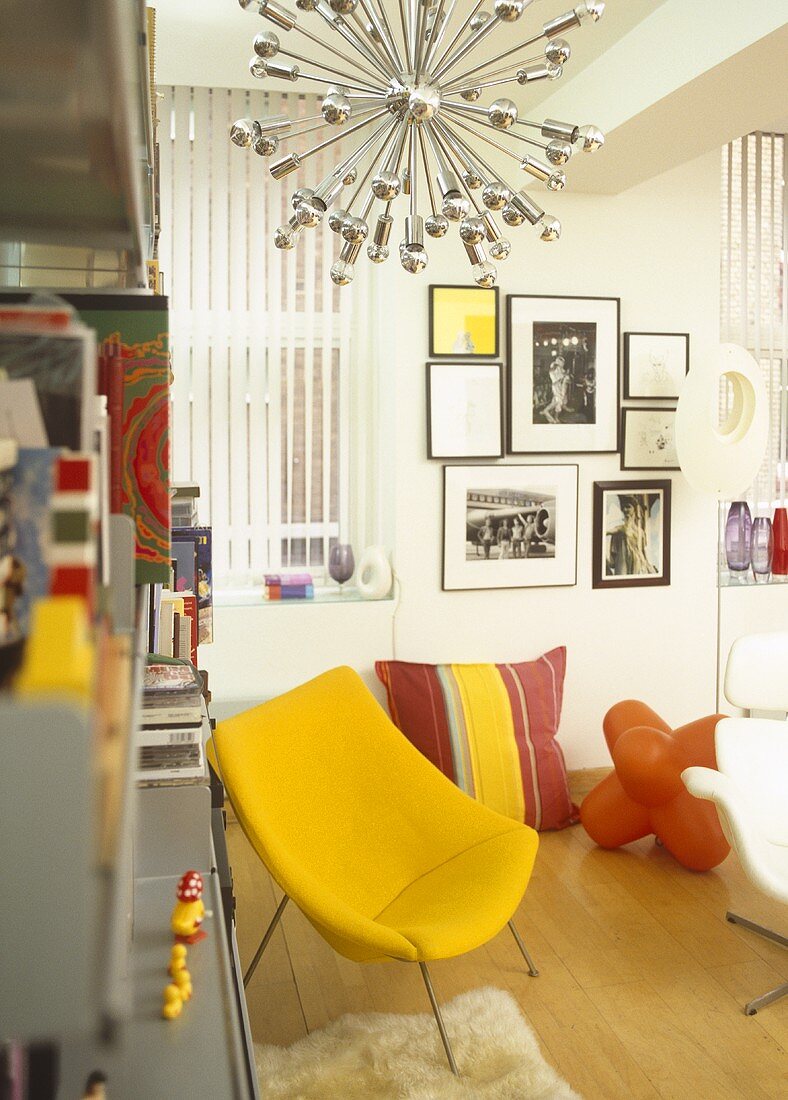 Gelber Sessel und oranger Plastikhocker im Wohnraum mit Designer Hängelampe