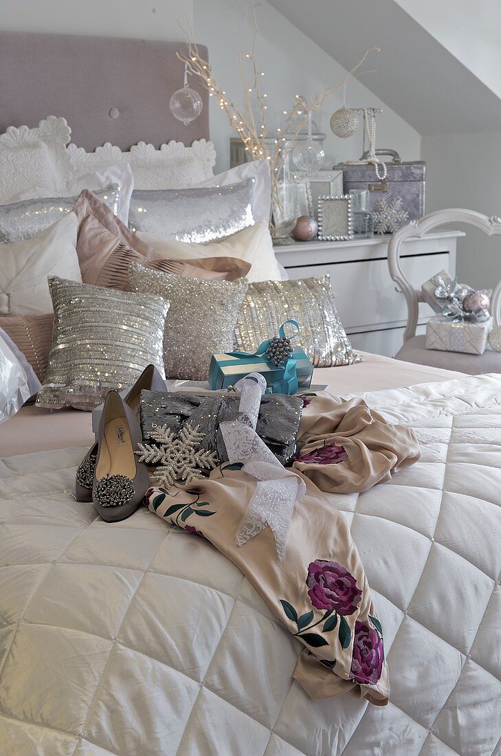 Damenschuhe auf weißem Plaid und Kissen aus glänzendem Stoff auf Bett