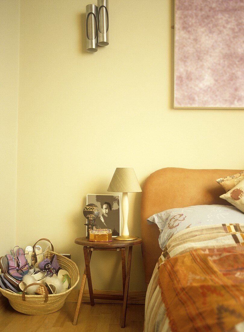 Rustikaler Nachttisch mit Lampe neben Bett vor gelber Wand