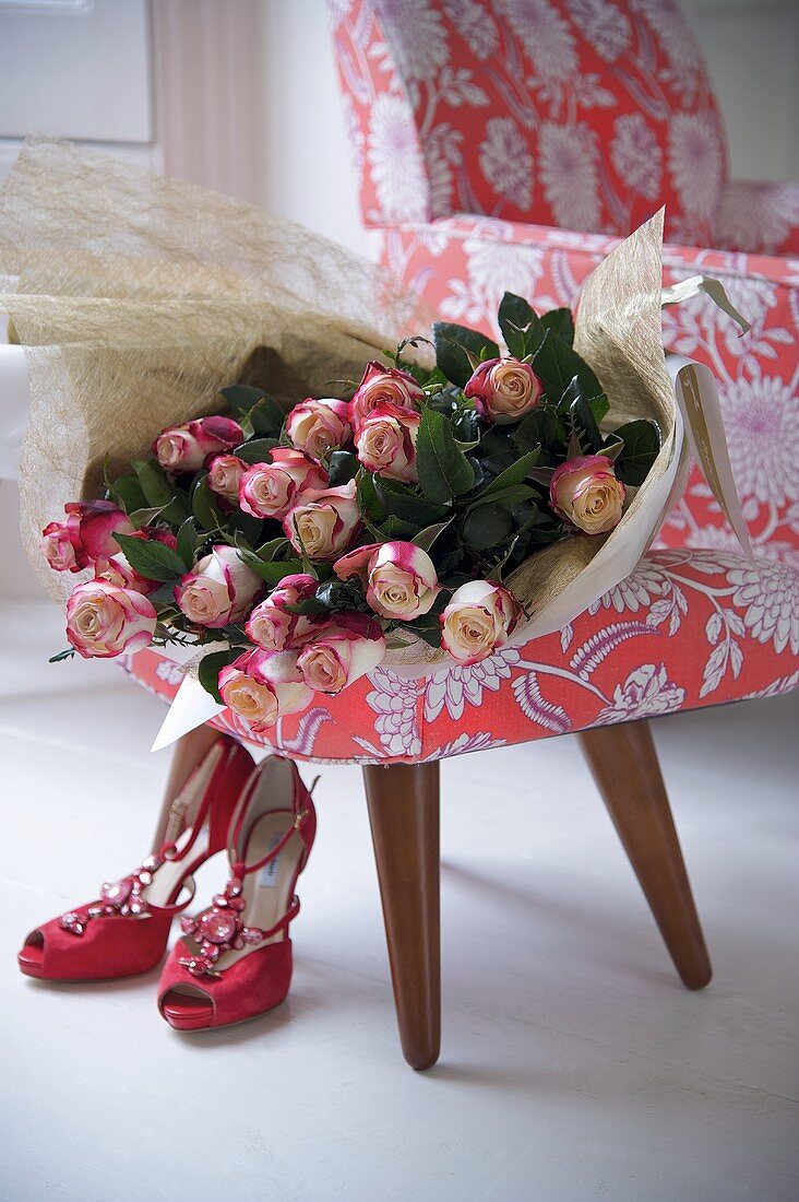 Roses on a 150s style armchair with red shoes on the floor