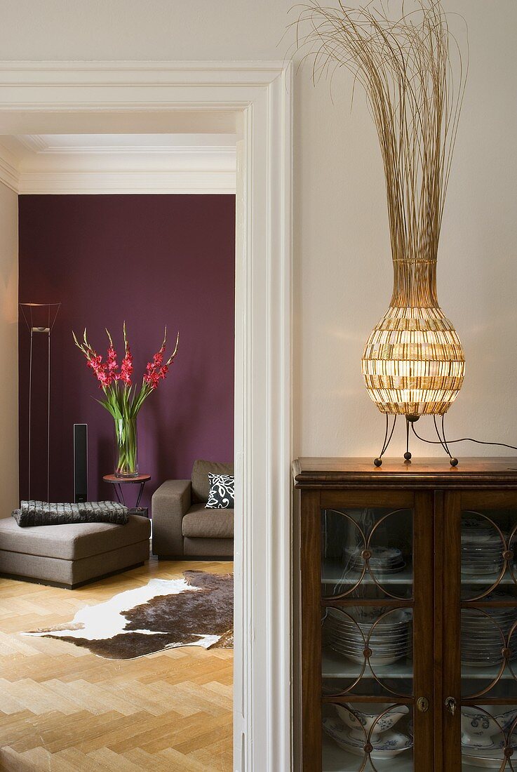 Display cabinet with table lamp next to an open door looking at a purple wall