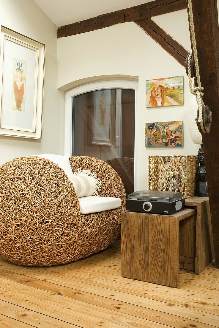 A designer woven armchair with a wooden side table in the corner of a room