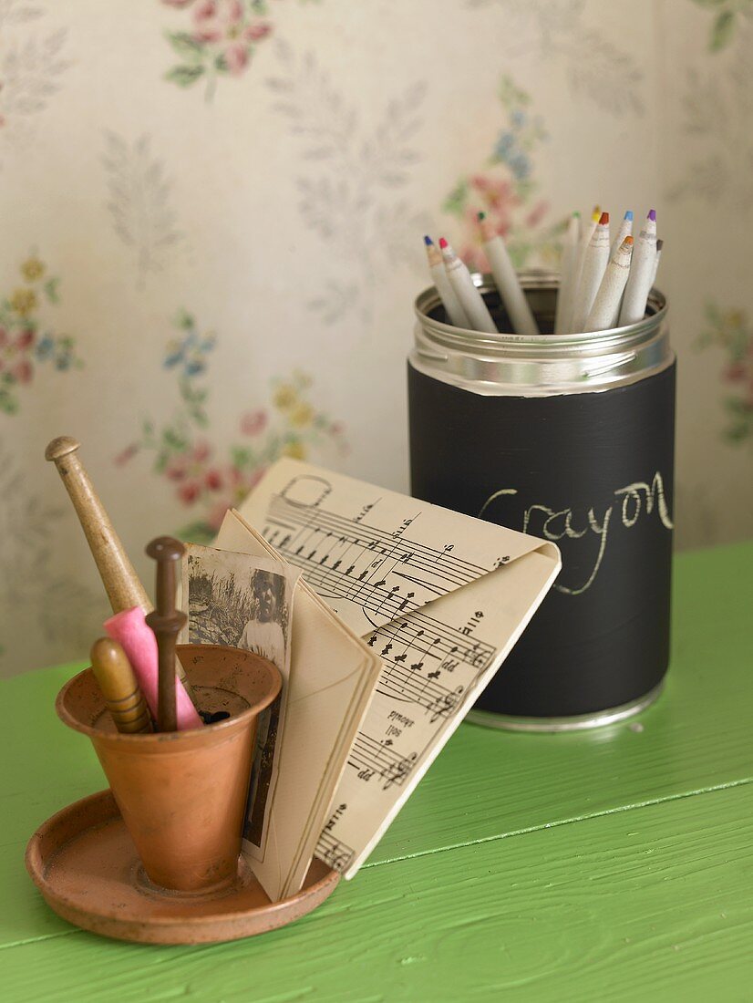 A clay pot and note paper next to a metal pot of coloured pencils