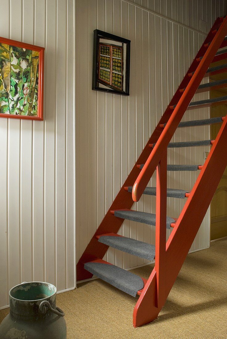 Red-brown wooden stairs in front of a white wood wall