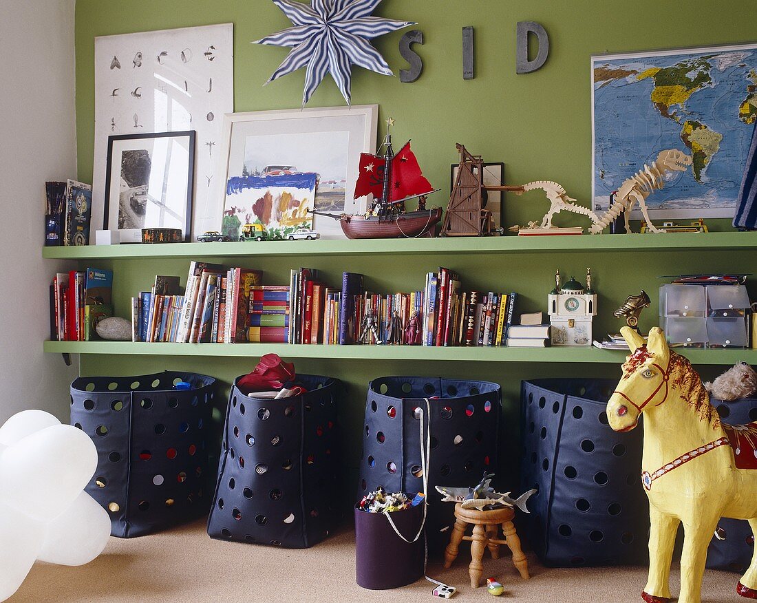 Wall shelves and blue storage containers in front of green wall in a child's room