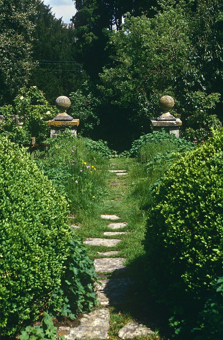 Wilder Garten mit Steinsäulen am Weg