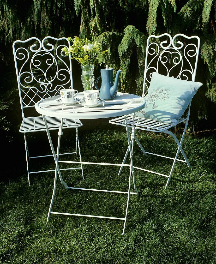 A coffee break in a garden with white metal chairs and a table