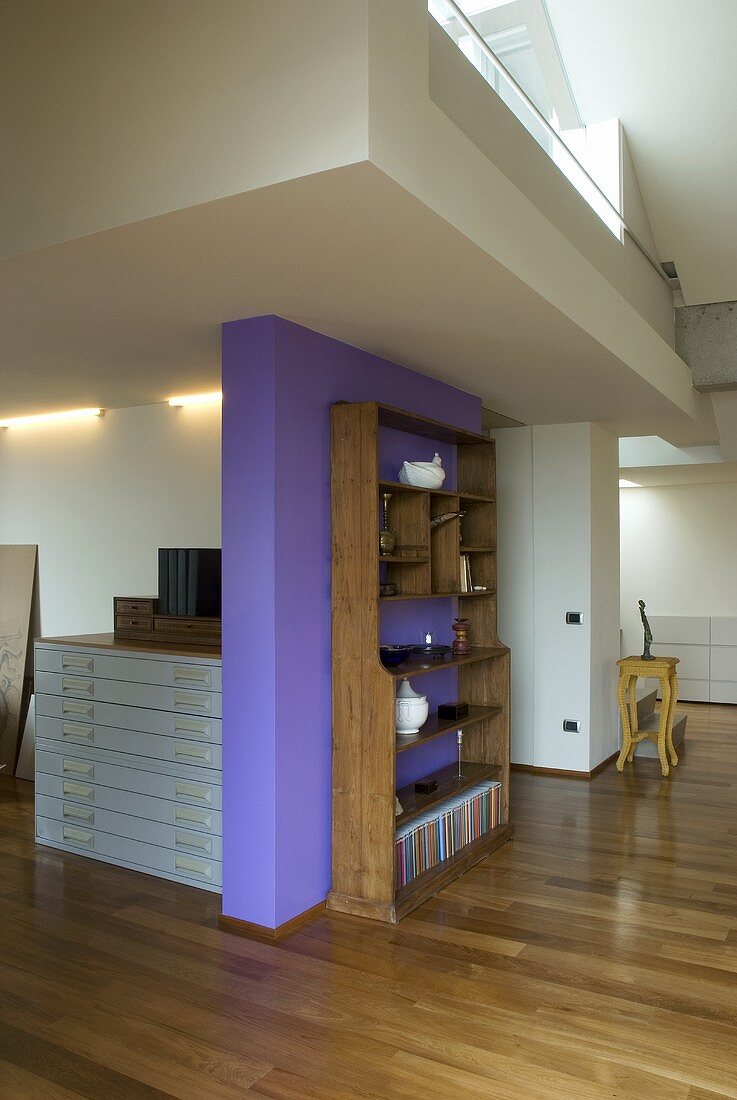 Offenes Wohnen - Bücherregal vor violetter Wand