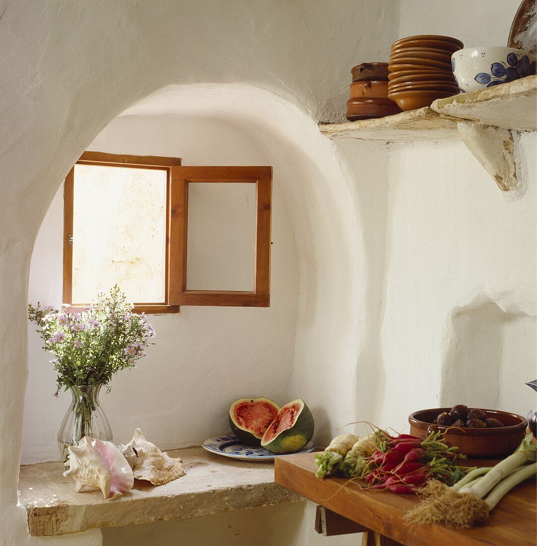 Muscheln und Wassermelone auf Ablage aus Stein unter Fenster in Alkoven im Mediterraner Küche und Gemüse auf Arbeitsplatte